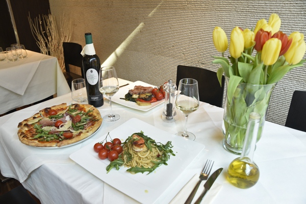 Ein schick gedeckter Tisch mit italienischen Speisen, einer Weinflasche und Tulpenstrauß