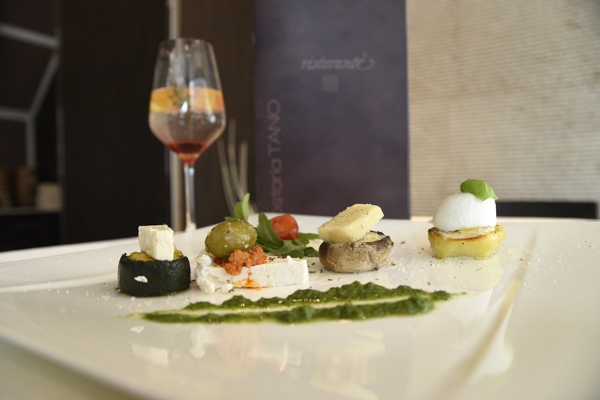 Ein kunstvoll angerichtetes vegetarisches Gericht mit Gemüse, Käse und Kräutersoße