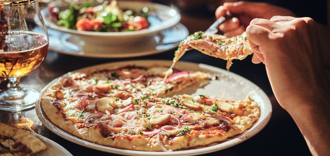 Junge Freunde essen während der Mittagspause Pizza und Salate in einem Straßencafé.